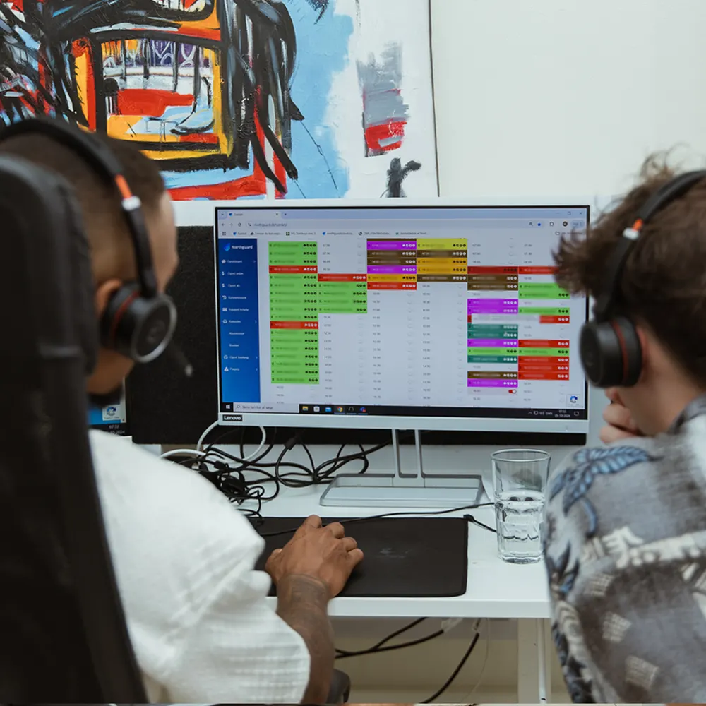 To Northguard-kolleger med headset arbejder i bookingsystemet på en fælles skærm